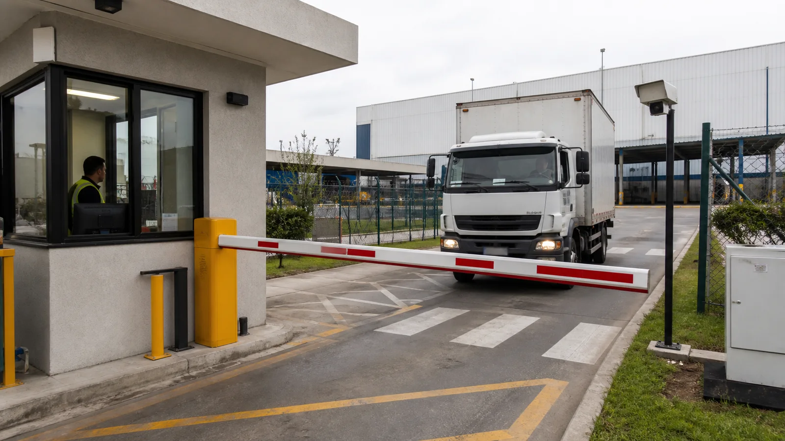 Caminhão aguardando diante de cancela em uma portaria industrial com guarita e câmera de identificação veicular