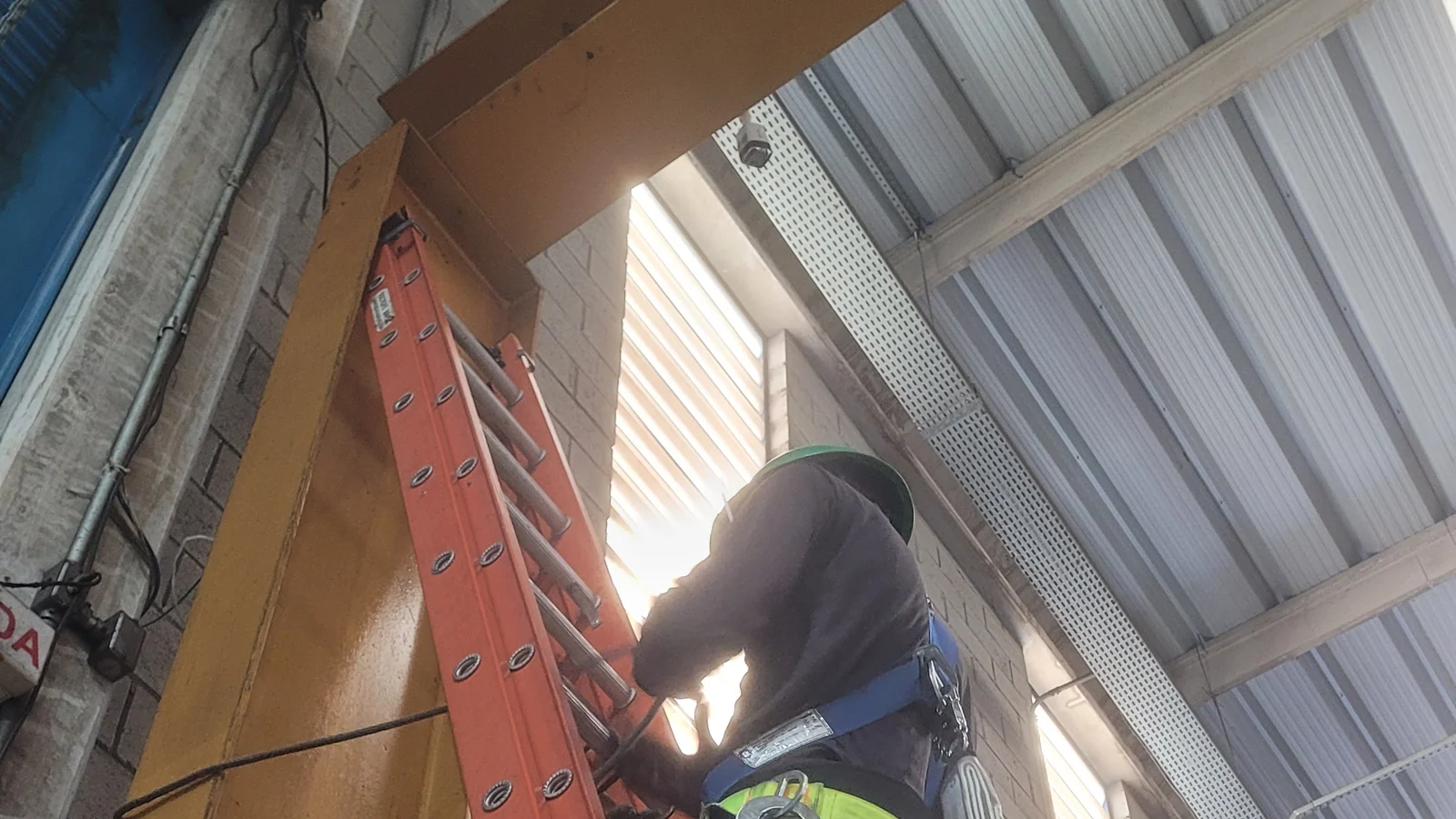 Técnico com equipamento de proteção trabalhando em ponto alto de instalação de CFTV