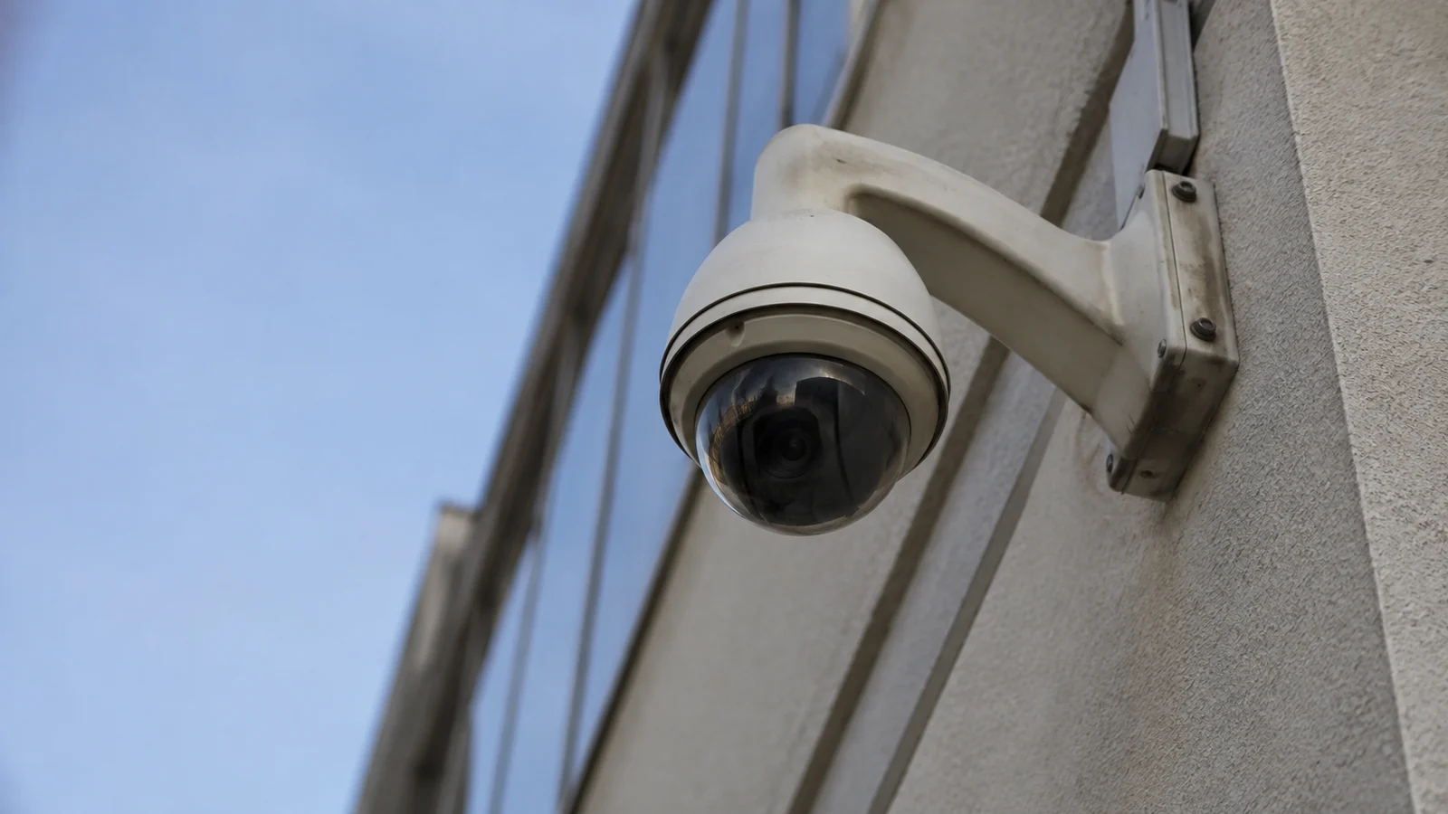 Câmera de segurança dome instalada na fachada de um prédio comercial, vista de baixo