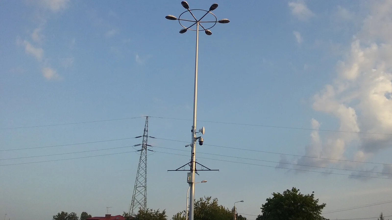 Poste alto com câmera de monitoramento e antena de transmissão de dados, contra um céu azul