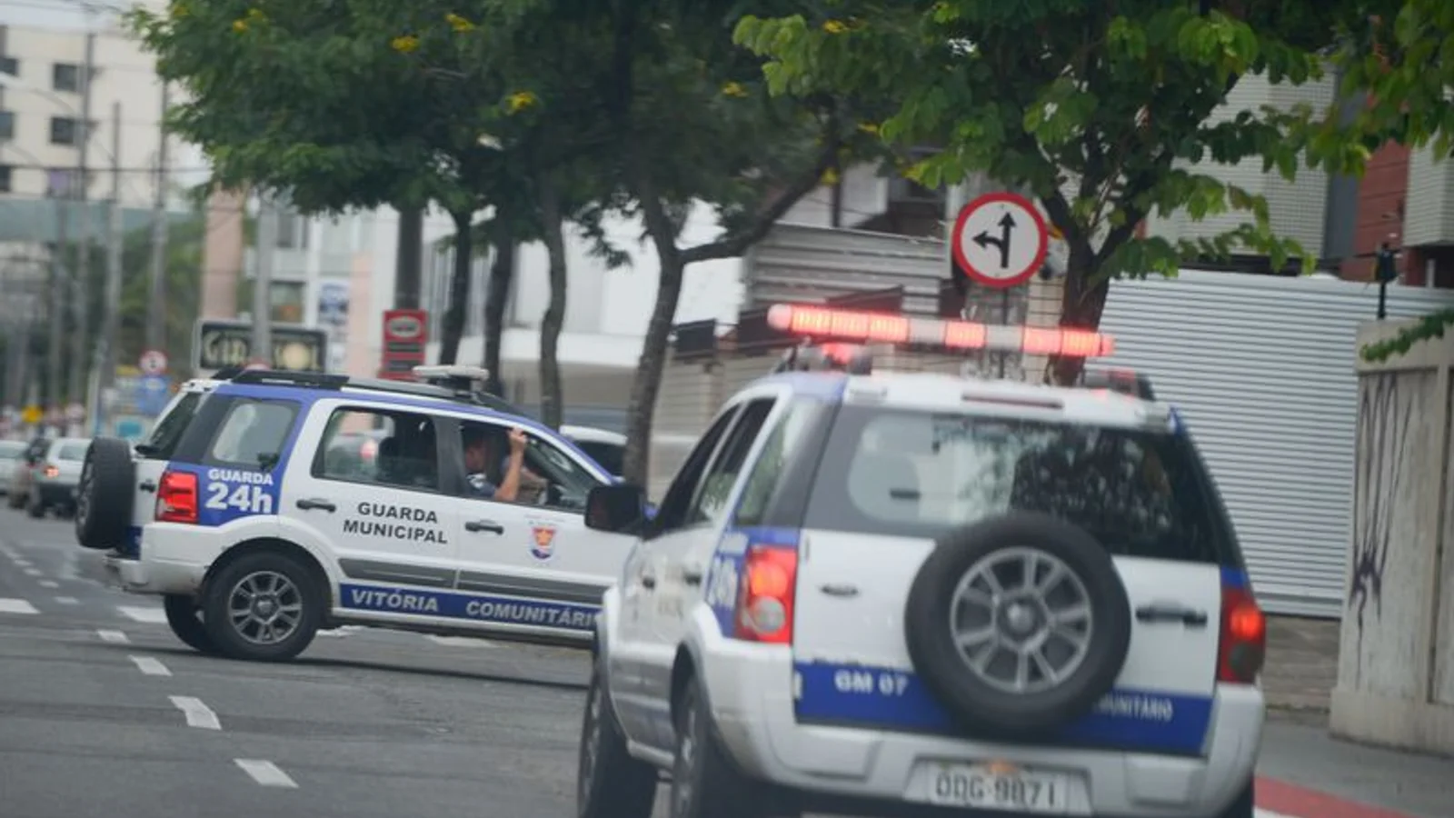 Duas viaturas da Guarda Municipal, com giroflex vermelho aceso, em uma rua urbana