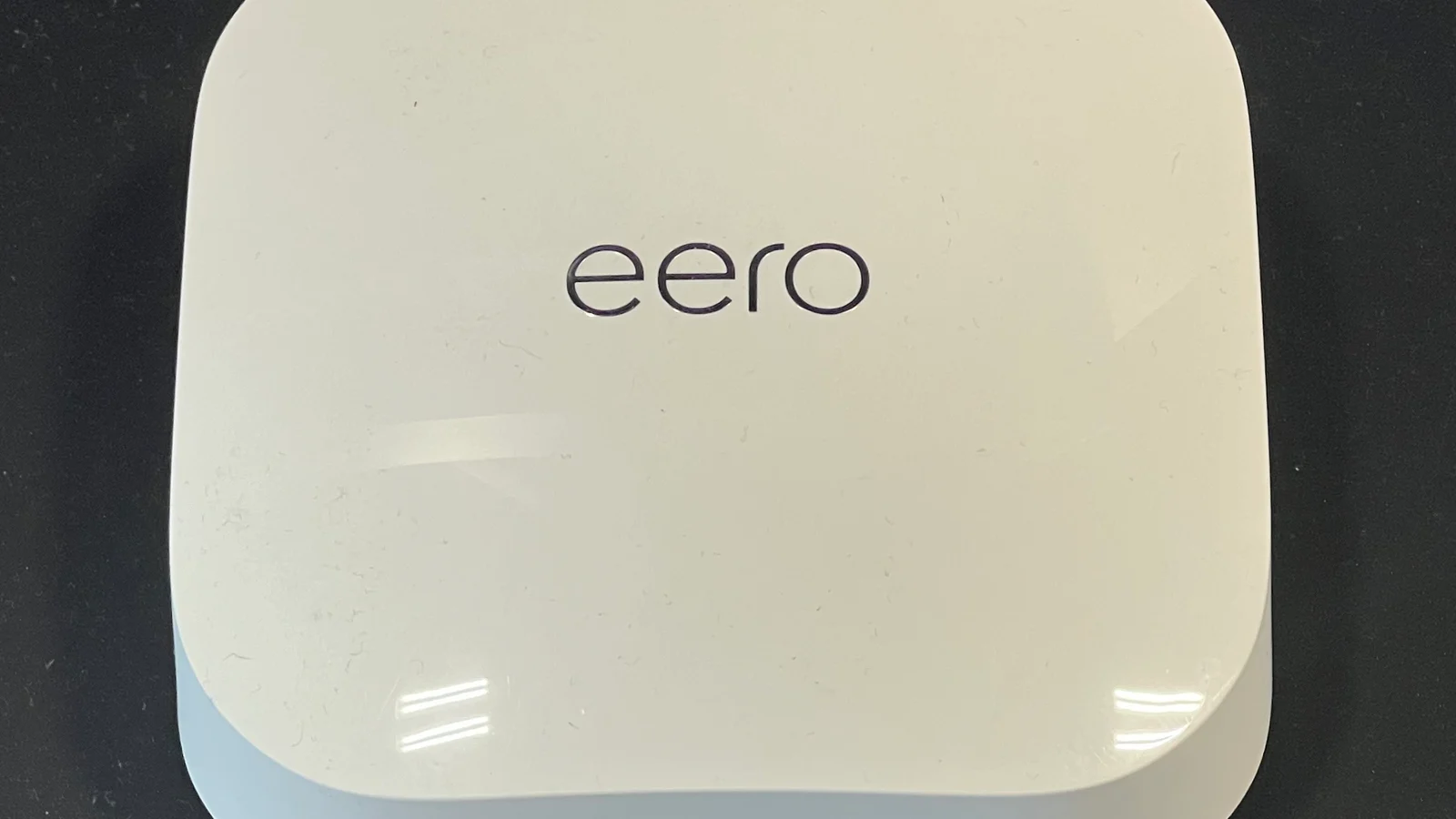 Roteador Wi-Fi 6E branco visto de cima em uma bancada escura