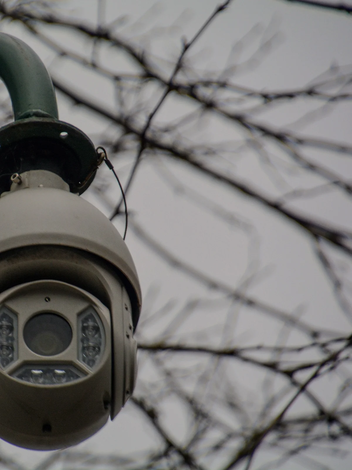Câmera dome de CFTV com iluminação infravermelha, vista de baixo contra um céu nublado
