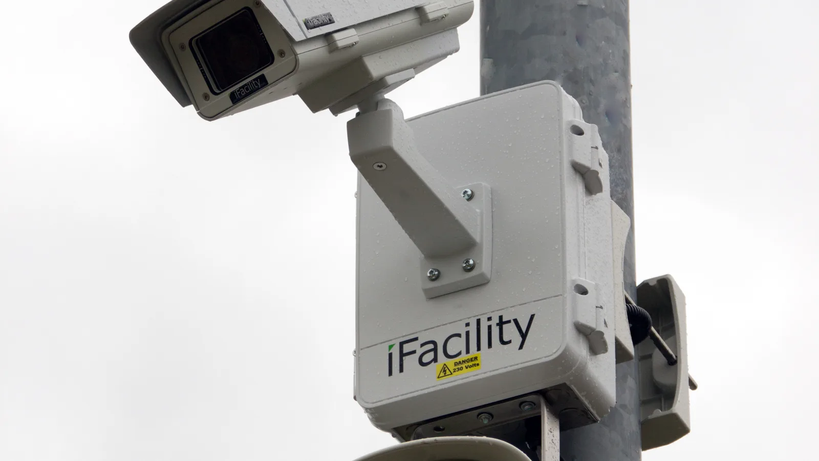 Câmera de segurança tipo dome instalada em poste, junto com alto-falante de áudio IP, em via pública