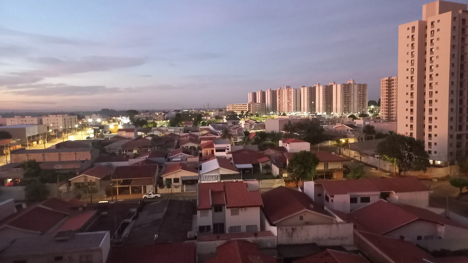 Vista aérea de bairro residencial de Americana, SP, ao entardecer, com prédios ao fundo