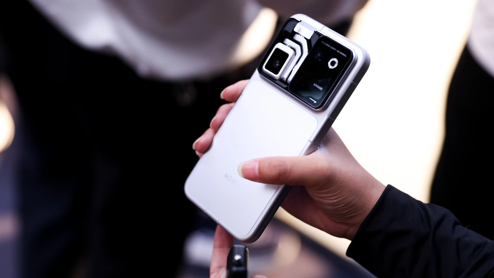 Close-up de mão segurando o Honor Robot Phone, mostrando em detalhe o módulo de câmera e o gimbal no topo do aparelho