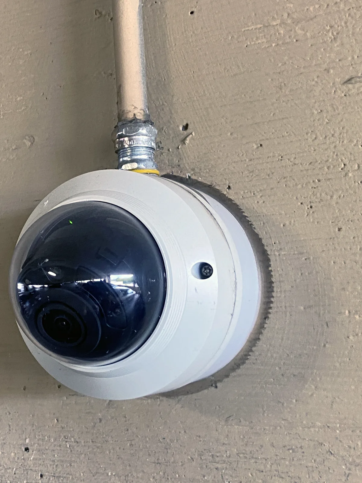 Câmera de segurança tipo dome instalada no teto de um estacionamento coberto