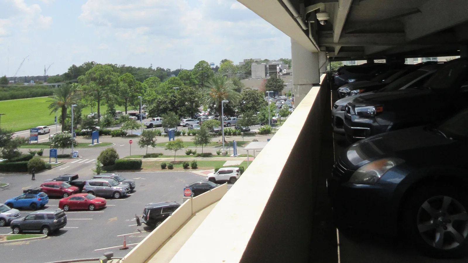 Câmera de segurança instalada na estrutura de um estacionamento de vários andares, com vista para a cidade ao fundo