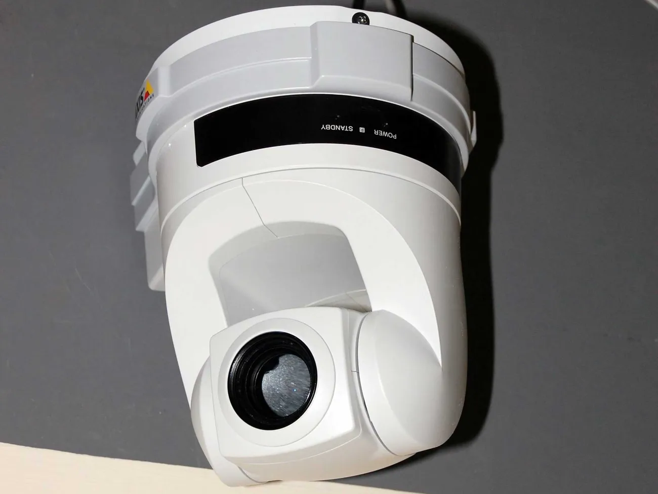 Câmera de segurança branca do tipo PTZ (pan-tilt-zoom) instalada em teto, com lente e indicadores visíveis