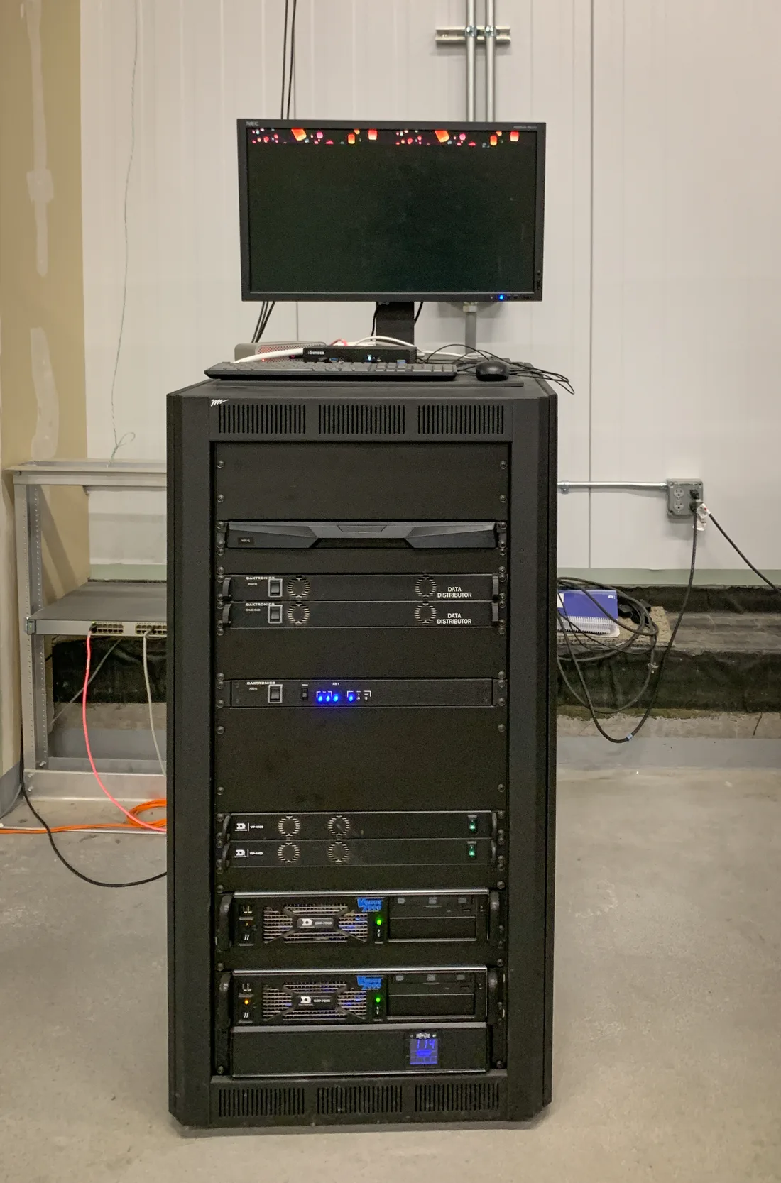 Rack de servidores de dados em ambiente técnico, com monitor e teclado no topo